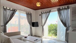 A modern living room with a wooden ceiling, a sofa, a coffee table, and a TV. - Satsuma Butik Otel (Seferihisar)