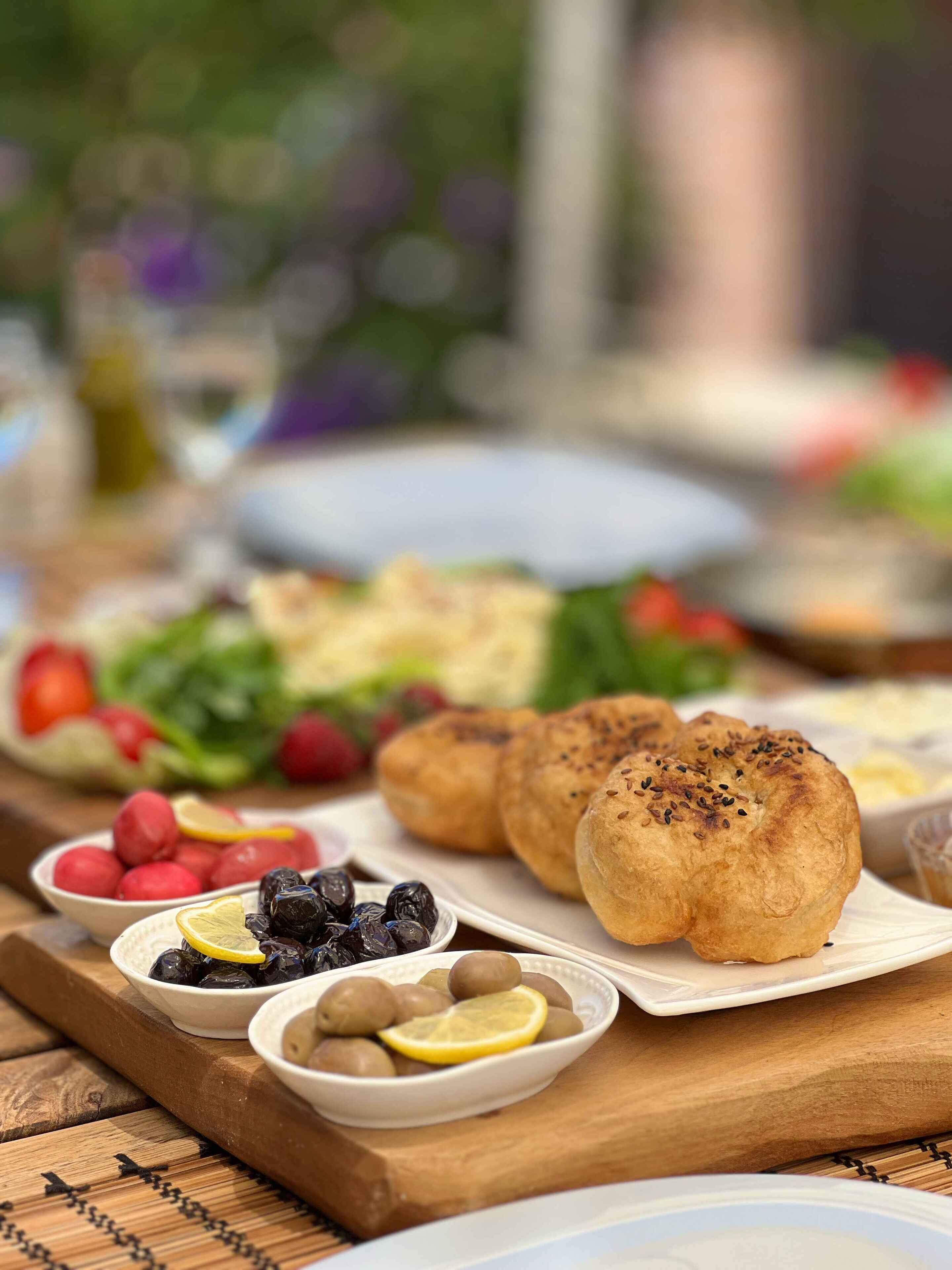 Uma mesa com diversos alimentos, incluindo pães, frutas e uma salada.