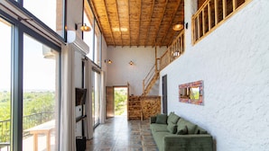 A spacious interior with a green sofa, a patterned floor, and a wooden staircase. - Satsuma Butik Otel (Seferihisar)