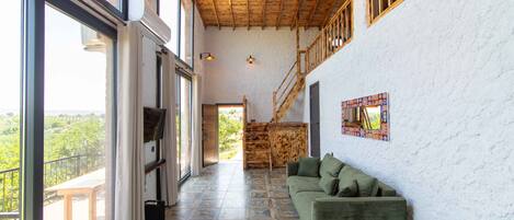 A spacious interior with a green sofa, a patterned floor, and a wooden staircase.