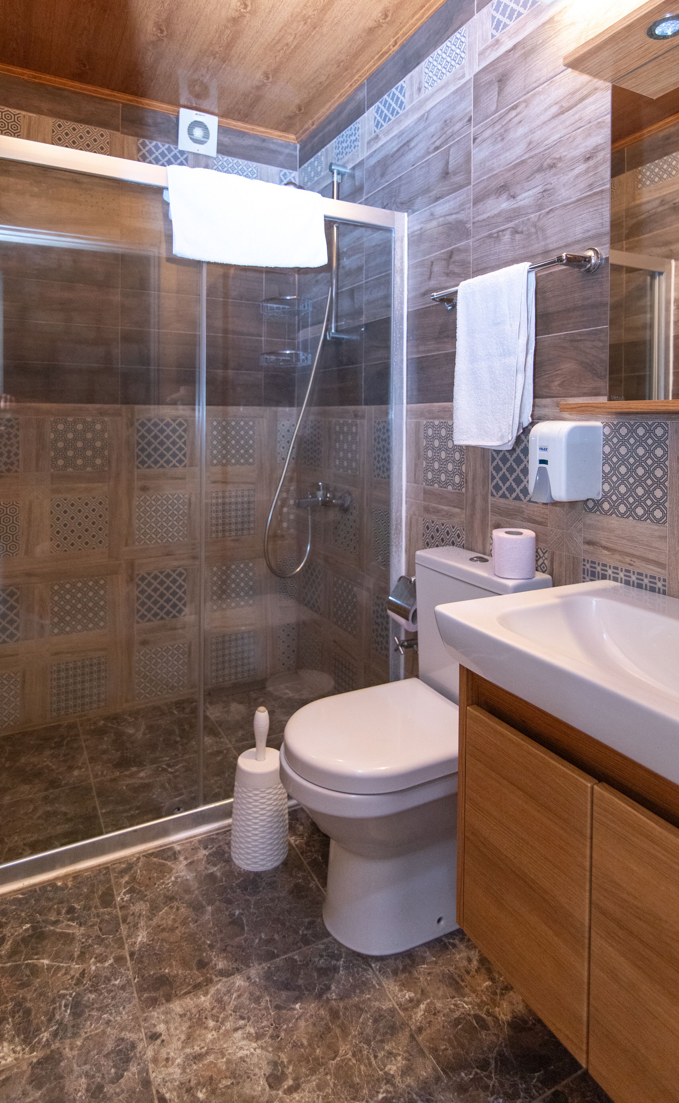 Un baño moderno con ducha envuelta en vidrio, inodoro y lavamanos.