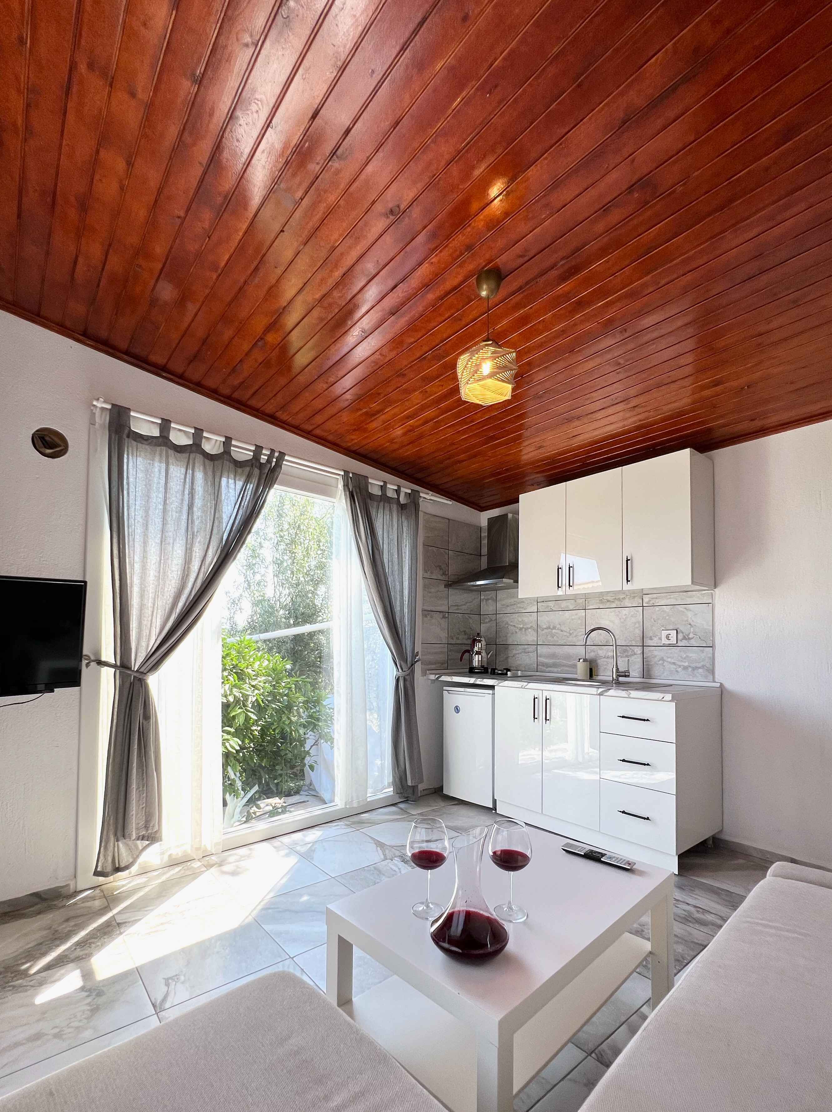 Une cuisine moderne avec des meubles blancs, un four encastré et une fenêtre avec des rideaux.