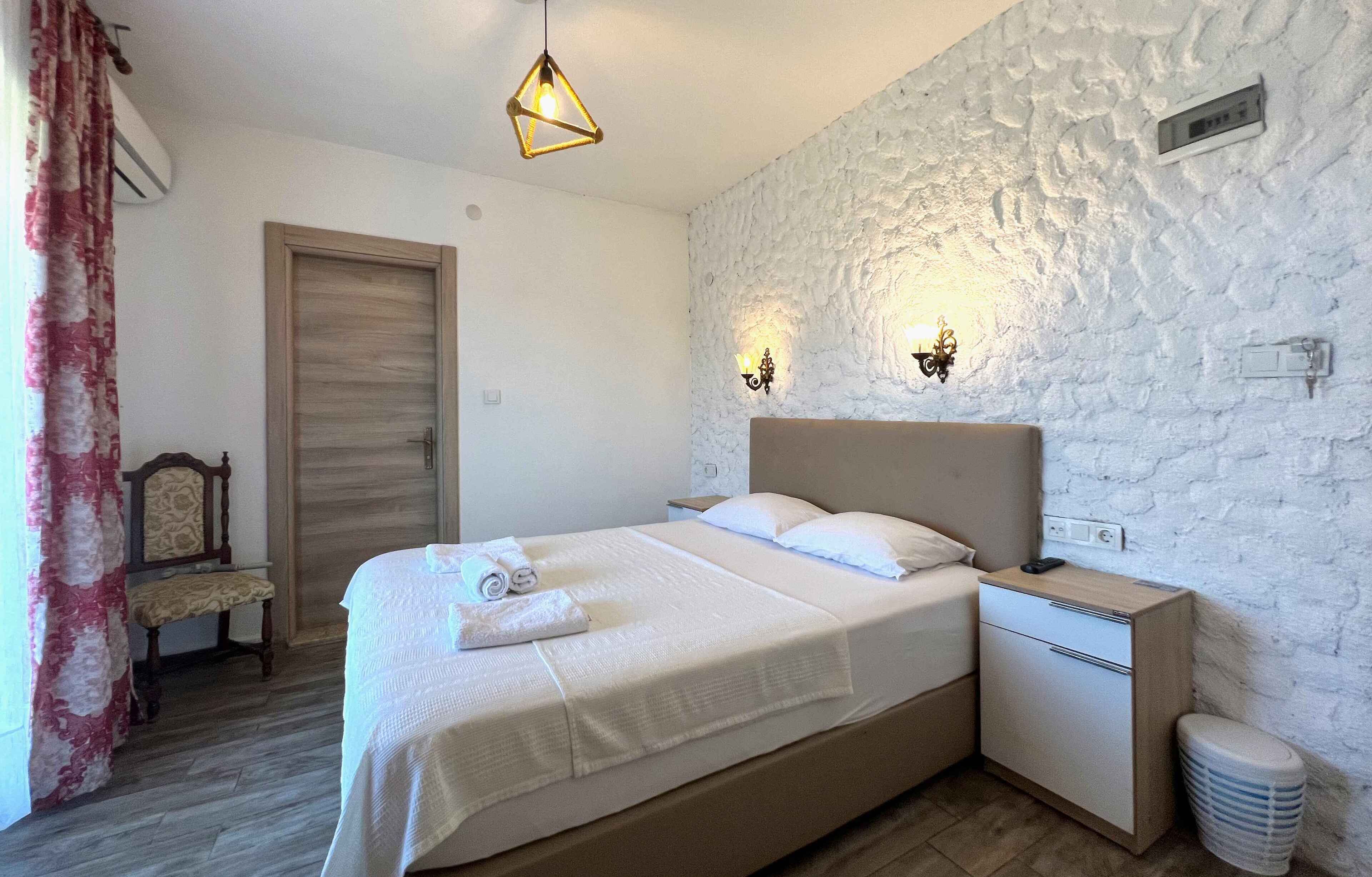 Un dormitorio ordenado con cama, mesita de noche y un mueble bajo.