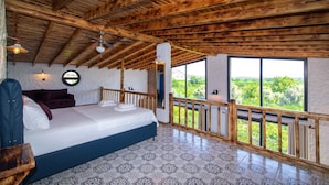 A bedroom with a wooden ceiling, a bed, a view through large windows, and a patterned floor. - Satsuma Butik Otel (Seferihisar)