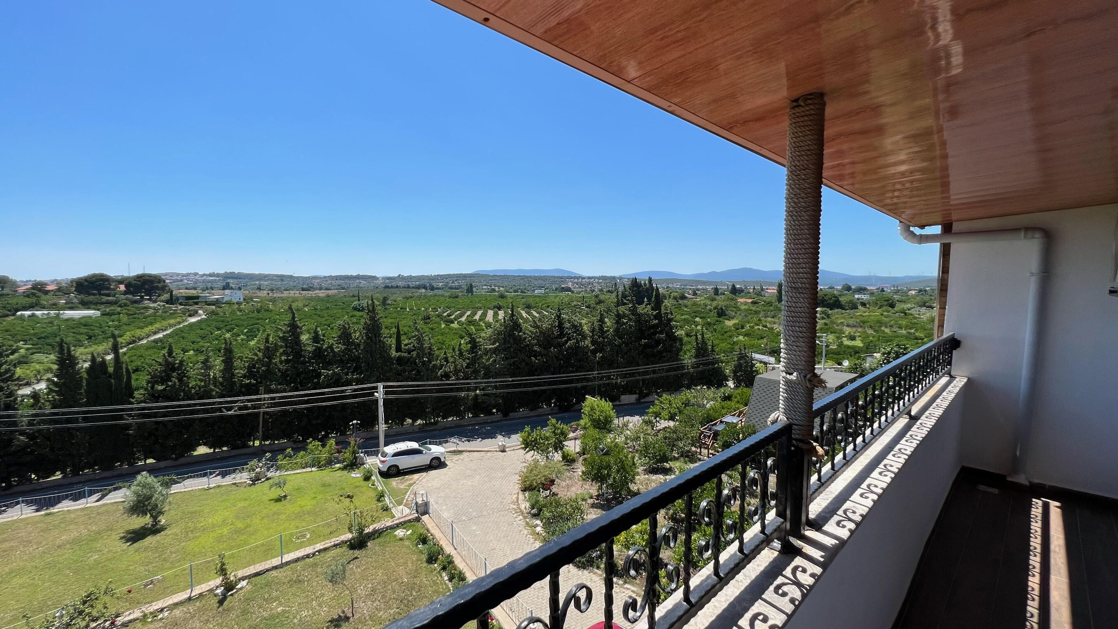 Un balcón con vistas a un paisaje verde y montañas distantes.