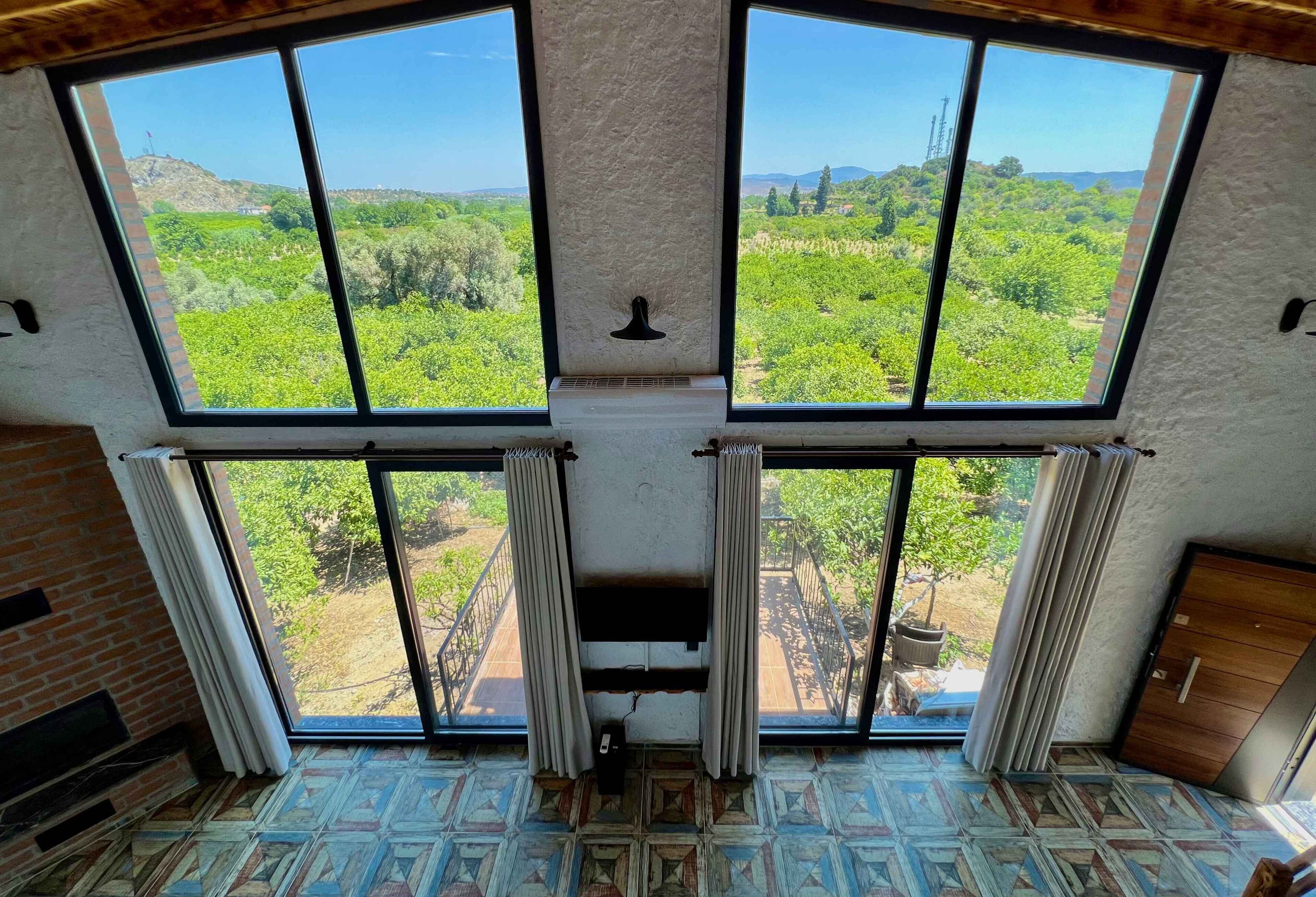 A room with large windows offering a view of a green landscape.