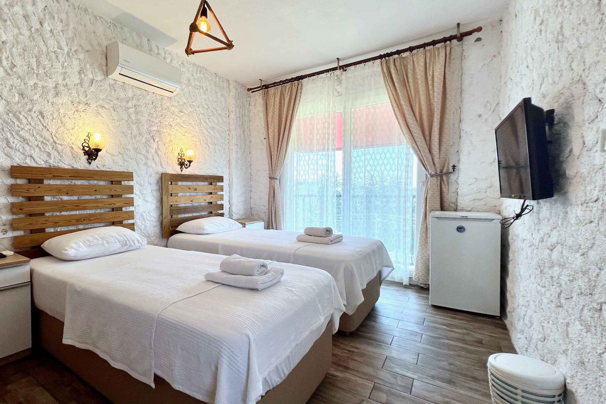 Quarto de hotel com duas camas, uma pequena mesa, televisão e minibar.