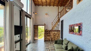 A spacious living area with a high ceiling, patterned floor tiles, a green sofa, and a staircase leading to an upper level. - Satsuma Butik Otel (Seferihisar)