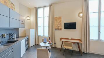 Una cocina moderna con pileta, estufa y muebles de cocina, un área de comedor con mesa y sillas, y un televisor montado en la pared.