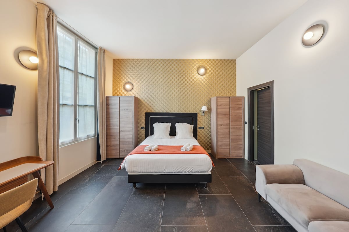 Une chambre d’hôtel moderne équipée d’un grand lit, d’un bureau, d’un canapé et d’une télévision.