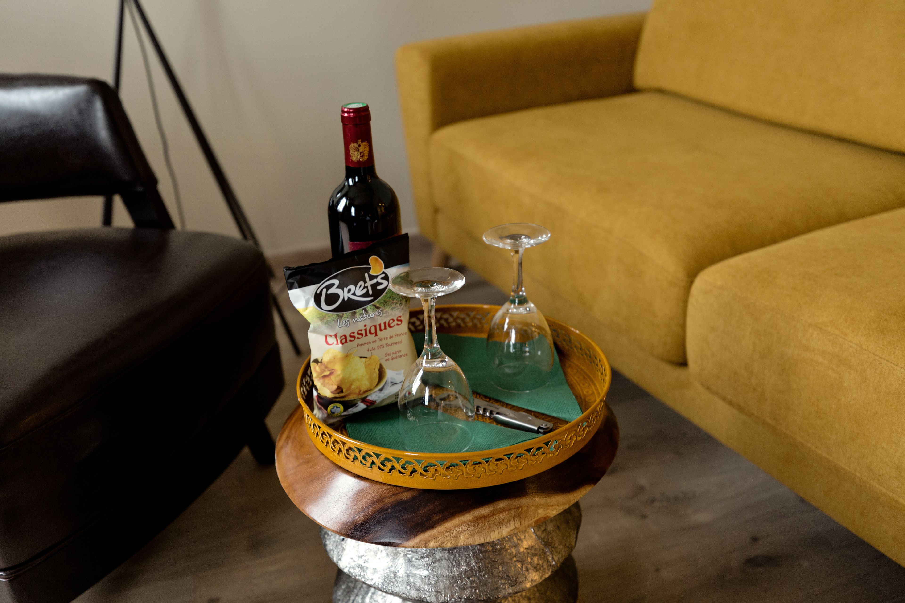 Ein Holztablett mit einer Weinflasche, einem Glas und einer Packung Brettes Classics auf einem Tisch.
