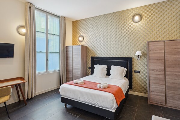 Una habitación de hotel moderna con una cama grande, un escritorio y un televisor.