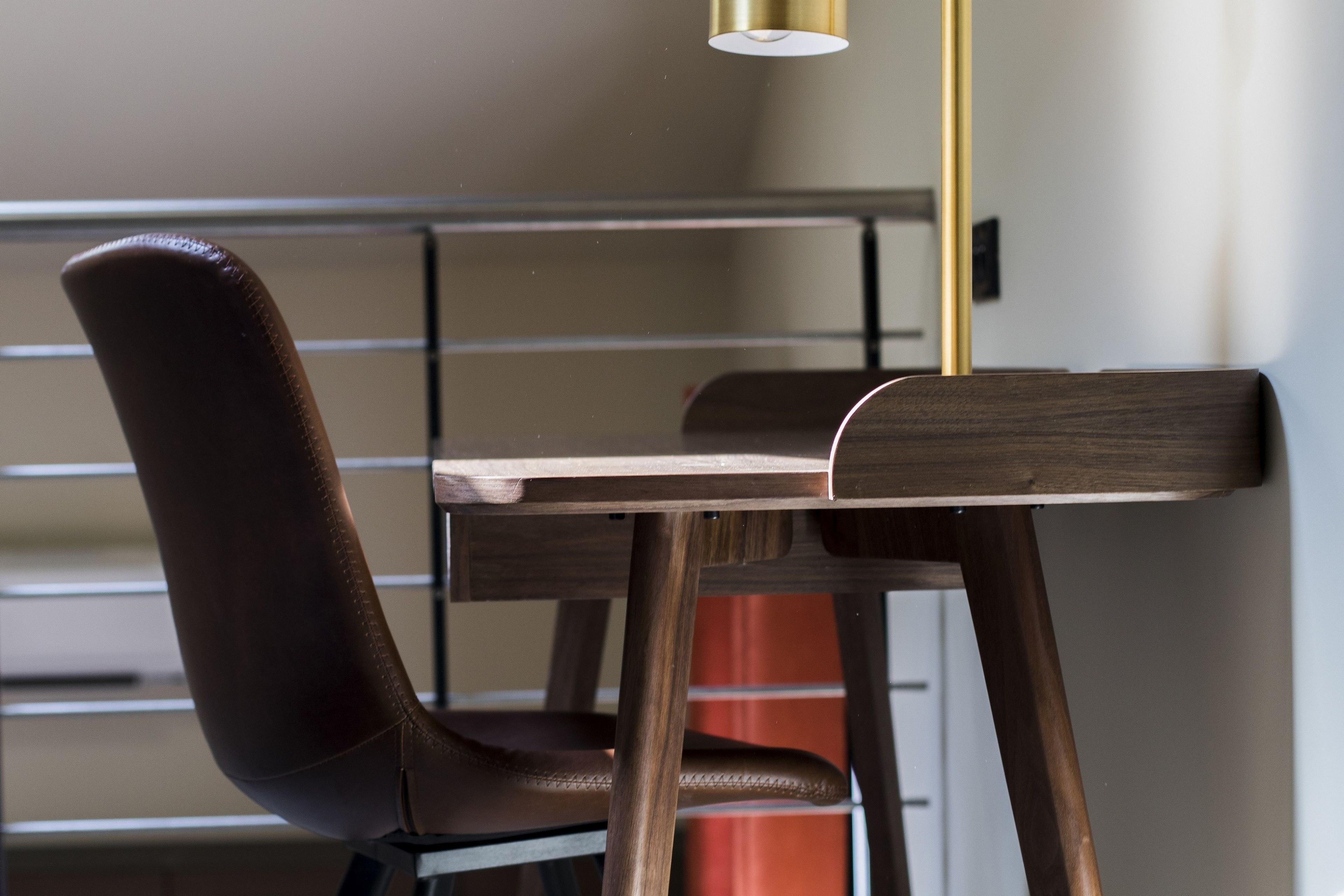 Una silla con respaldo alto y una mesa de madera con estructura metálica.