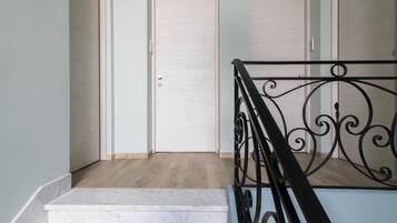 Una escalera con descansillo de mármol y barandilla de hierro forjado.