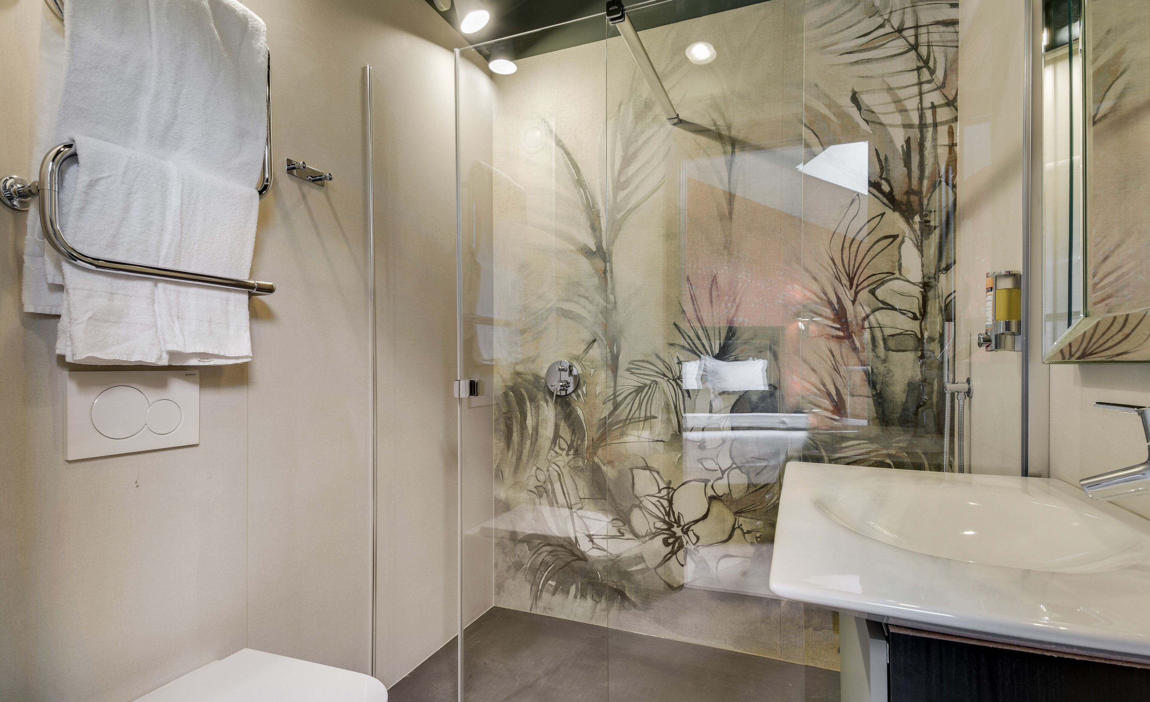 Une salle de bain moderne avec une douche à parois de verre, un lavabo blanc et un porte-serviettes.