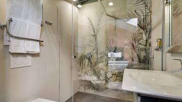 Une salle de bain moderne avec une douche à parois de verre, un lavabo blanc et un porte-serviettes.