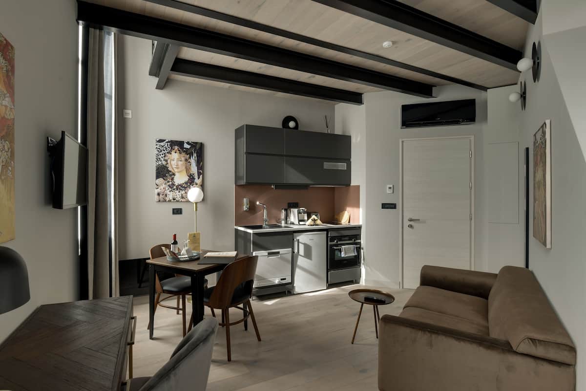 Un salon moderne comprenant un canapé, une table à manger avec des chaises et un coin cuisine avec des placards et des appareils électroménagers.