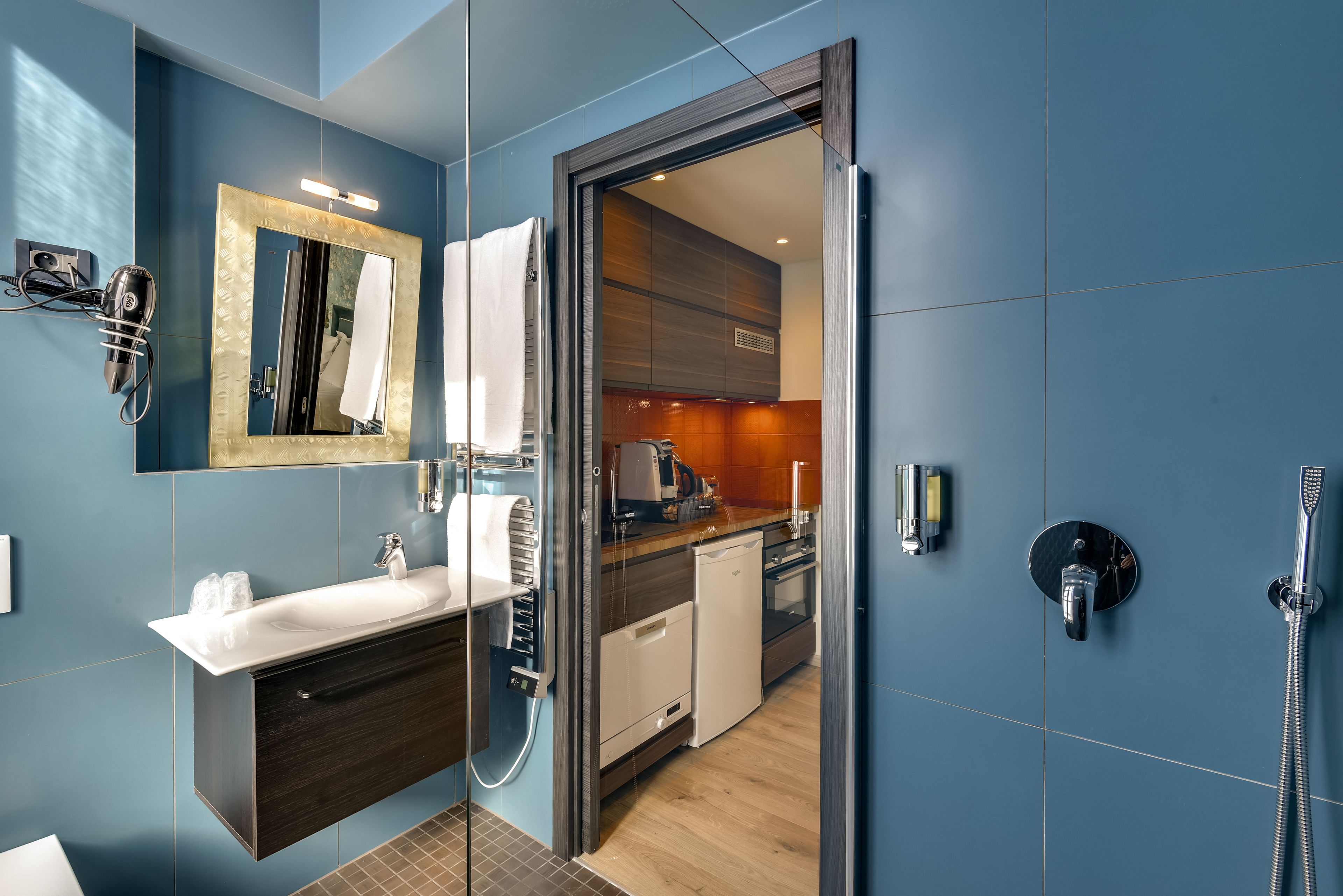 Une salle de bain moderne avec un grand miroir, un lavabo, une douche et un espace de douche clos par des parois de verre.