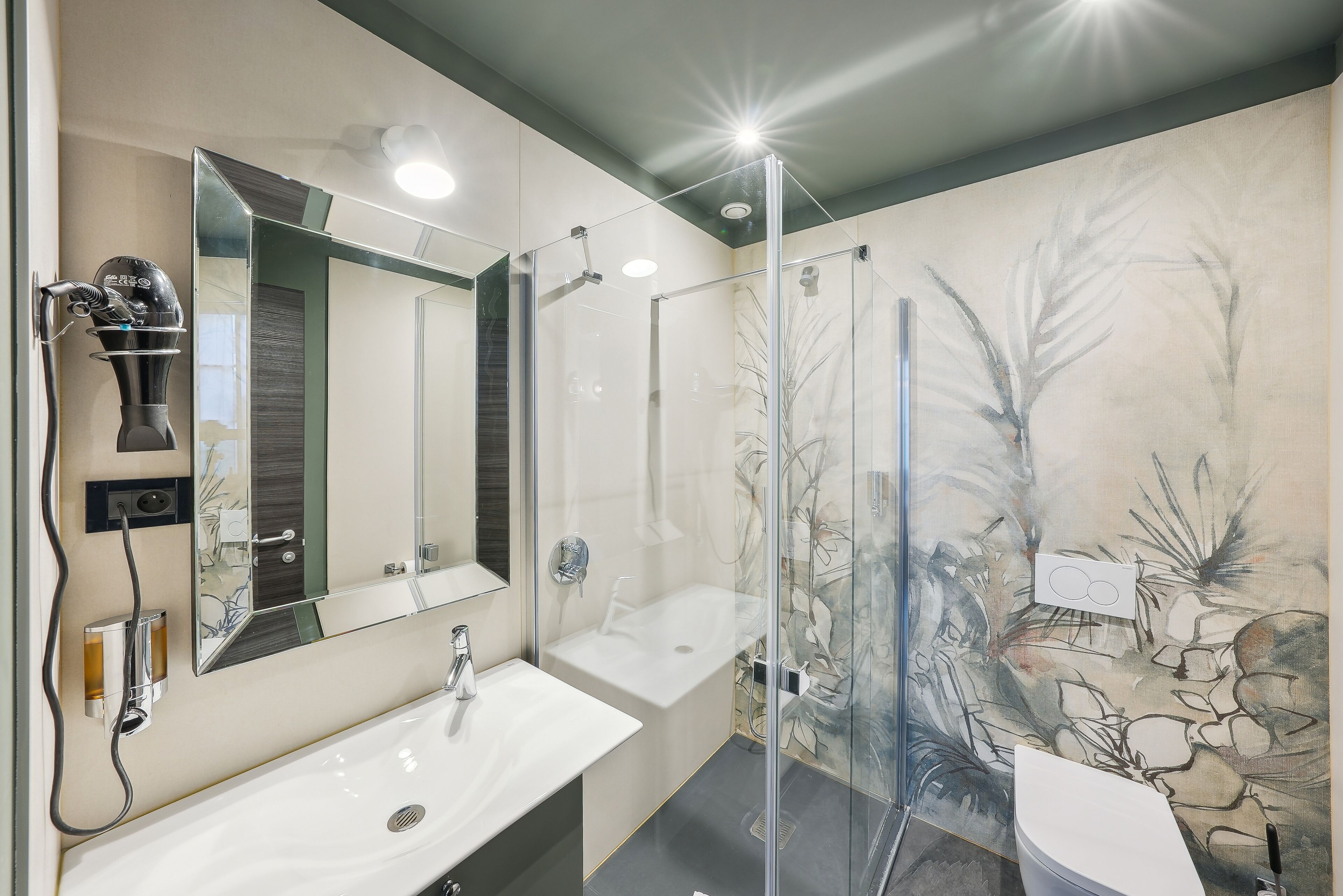 Een moderne badkamer met een douchecabine van glas, een grote spiegel en een wastafel.