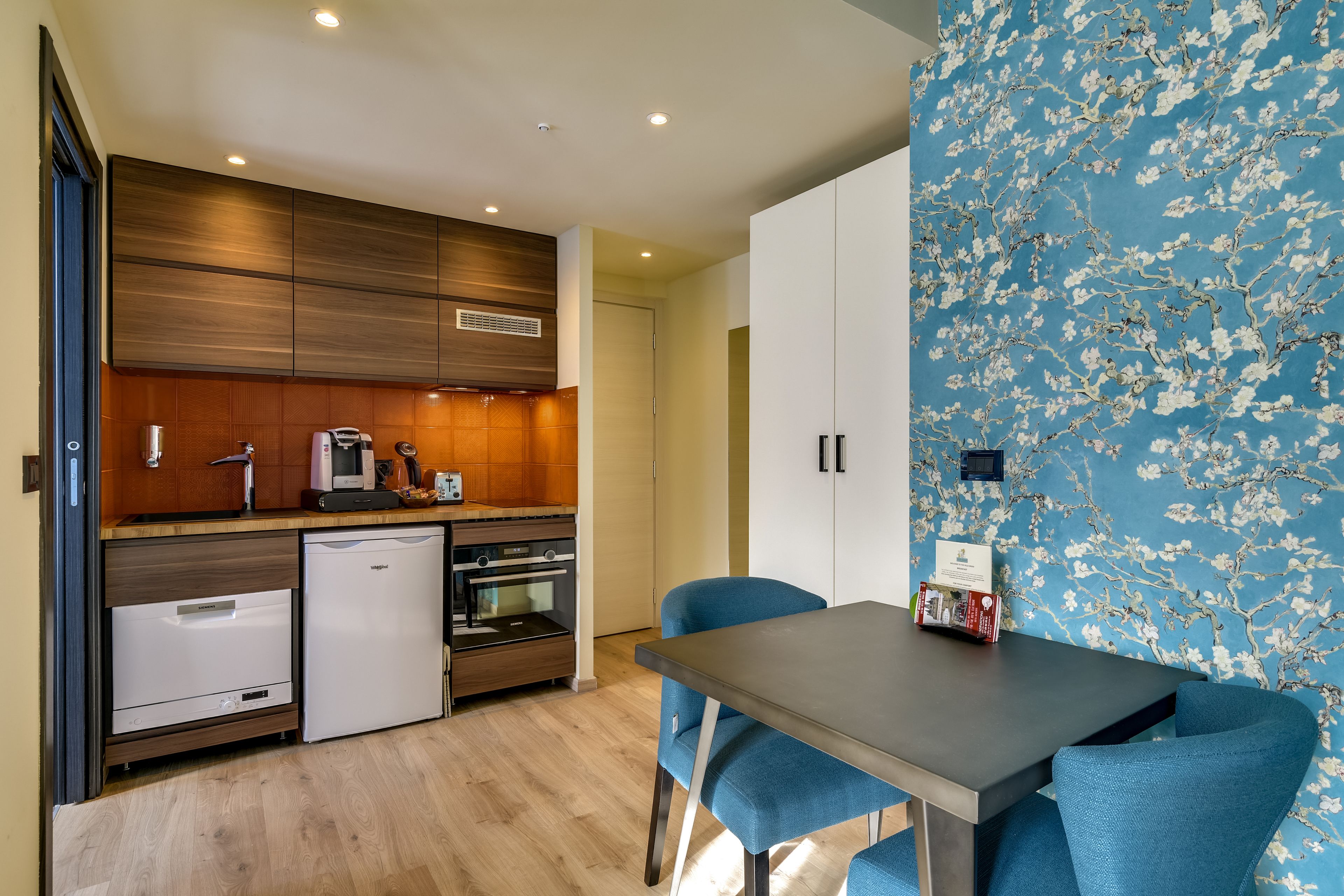 Una cocina moderna con armarios de madera, horno empotrado y lavavajillas compacto.
