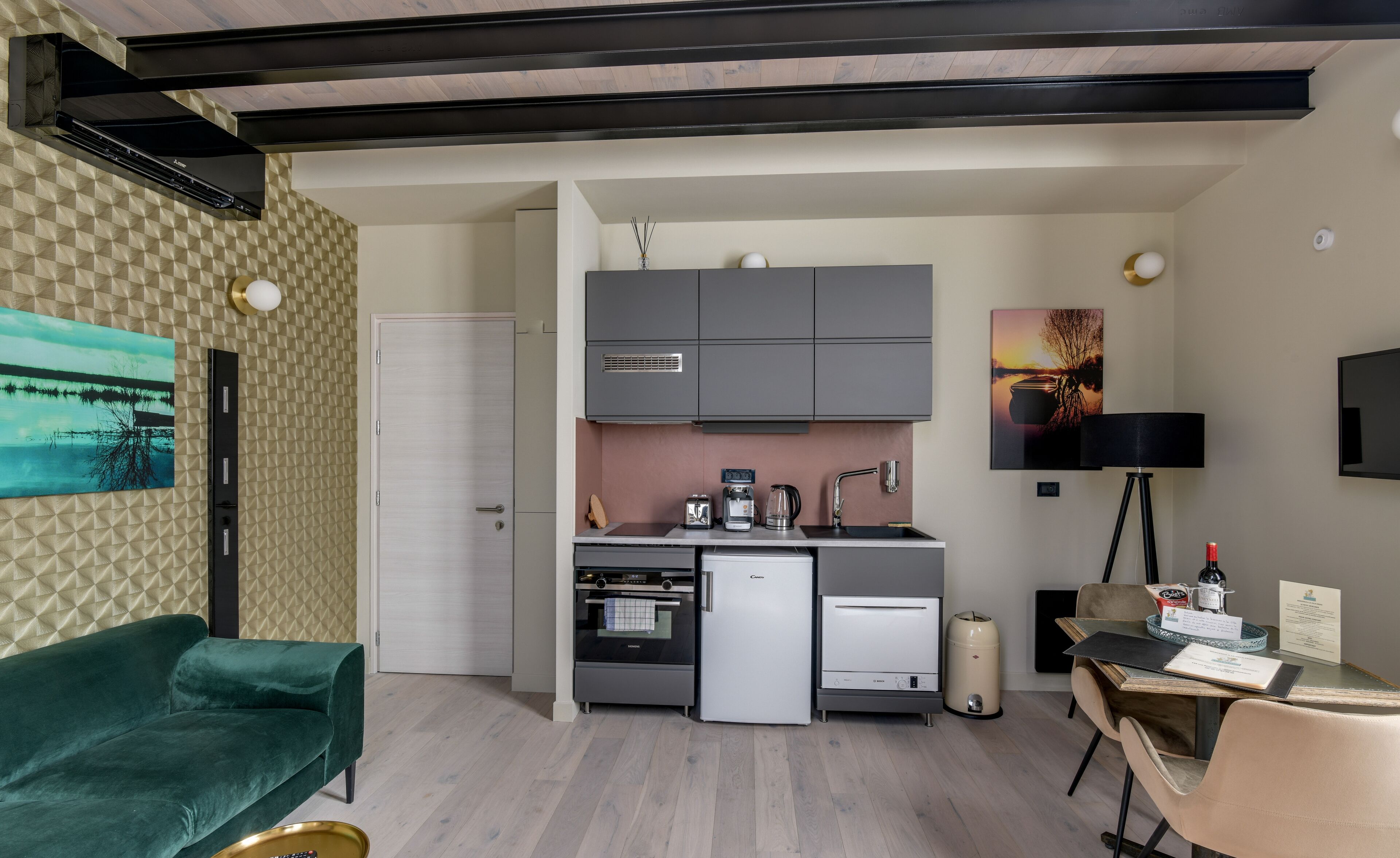 A compact kitchen with modern appliances, a dining area with a table and chairs, and a living space with a sofa.