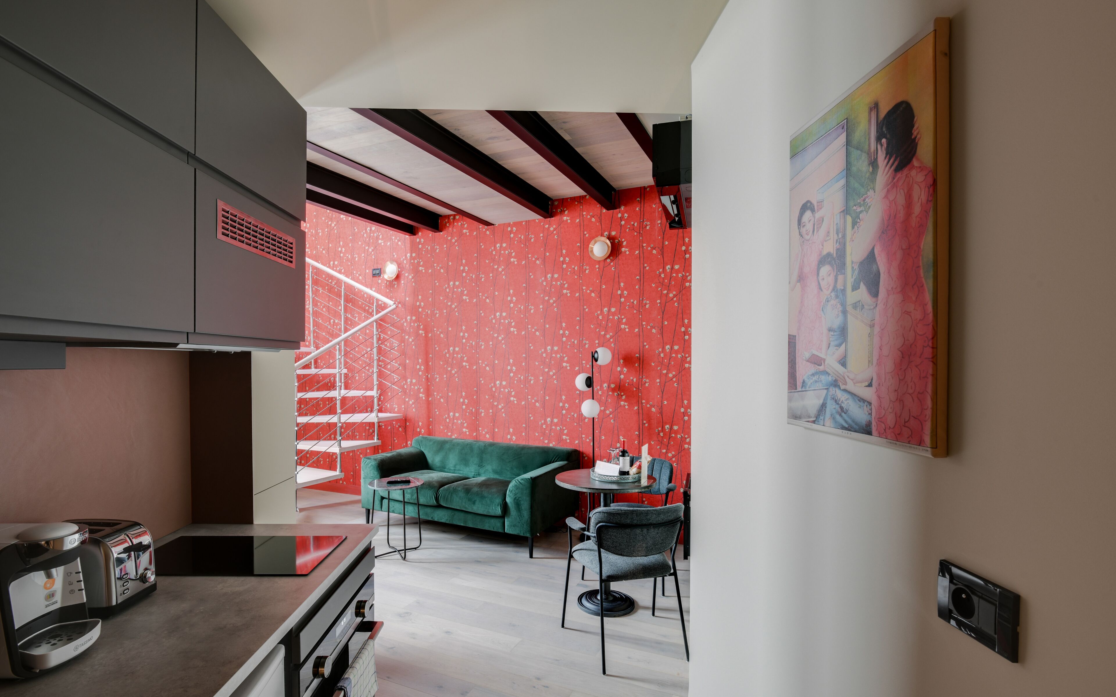 A modern living room with a green sofa, a small round table, and a staircase leading to an upper level.