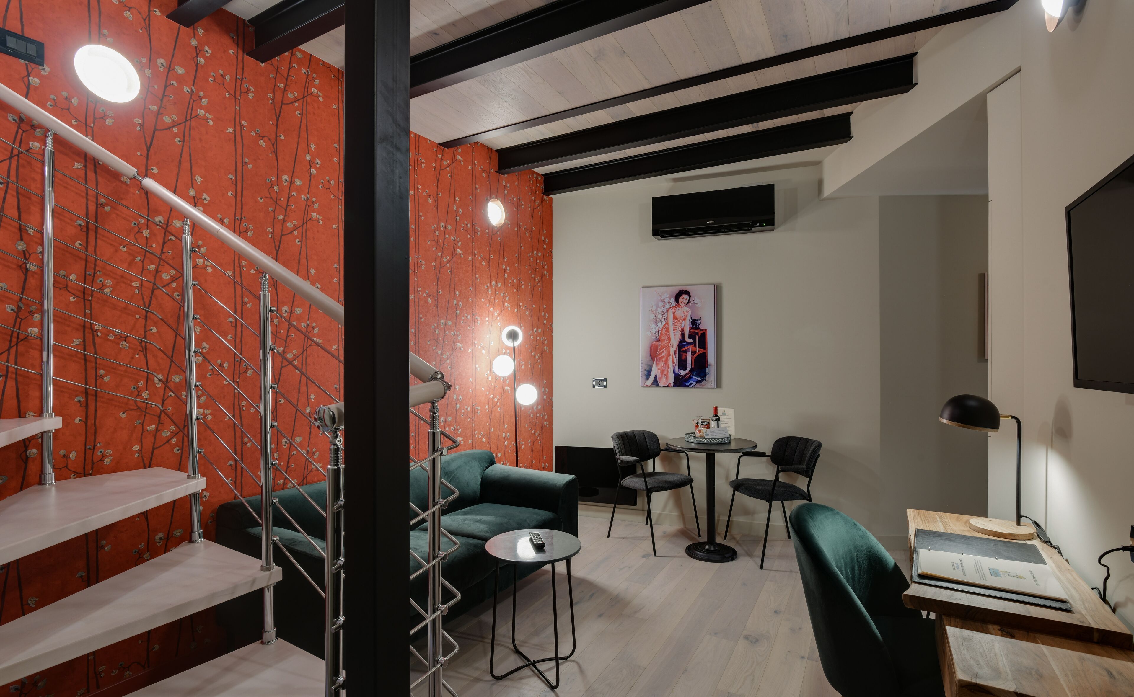Un interior moderno con una escalera, sofás verdes, una mesa redonda y un cuadro en la pared.
