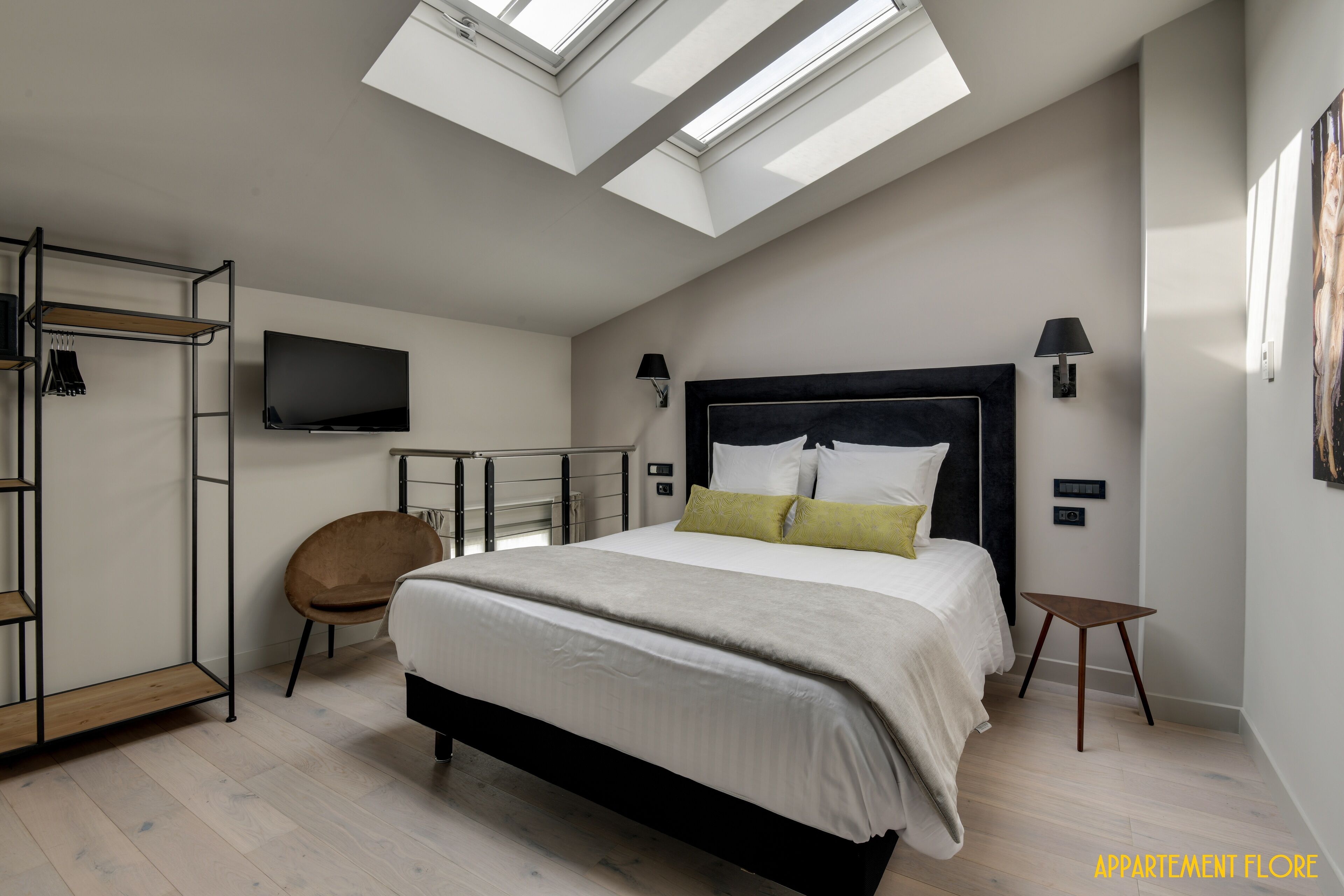 Un dormitorio con cama, televisión, silla y tragaluz.