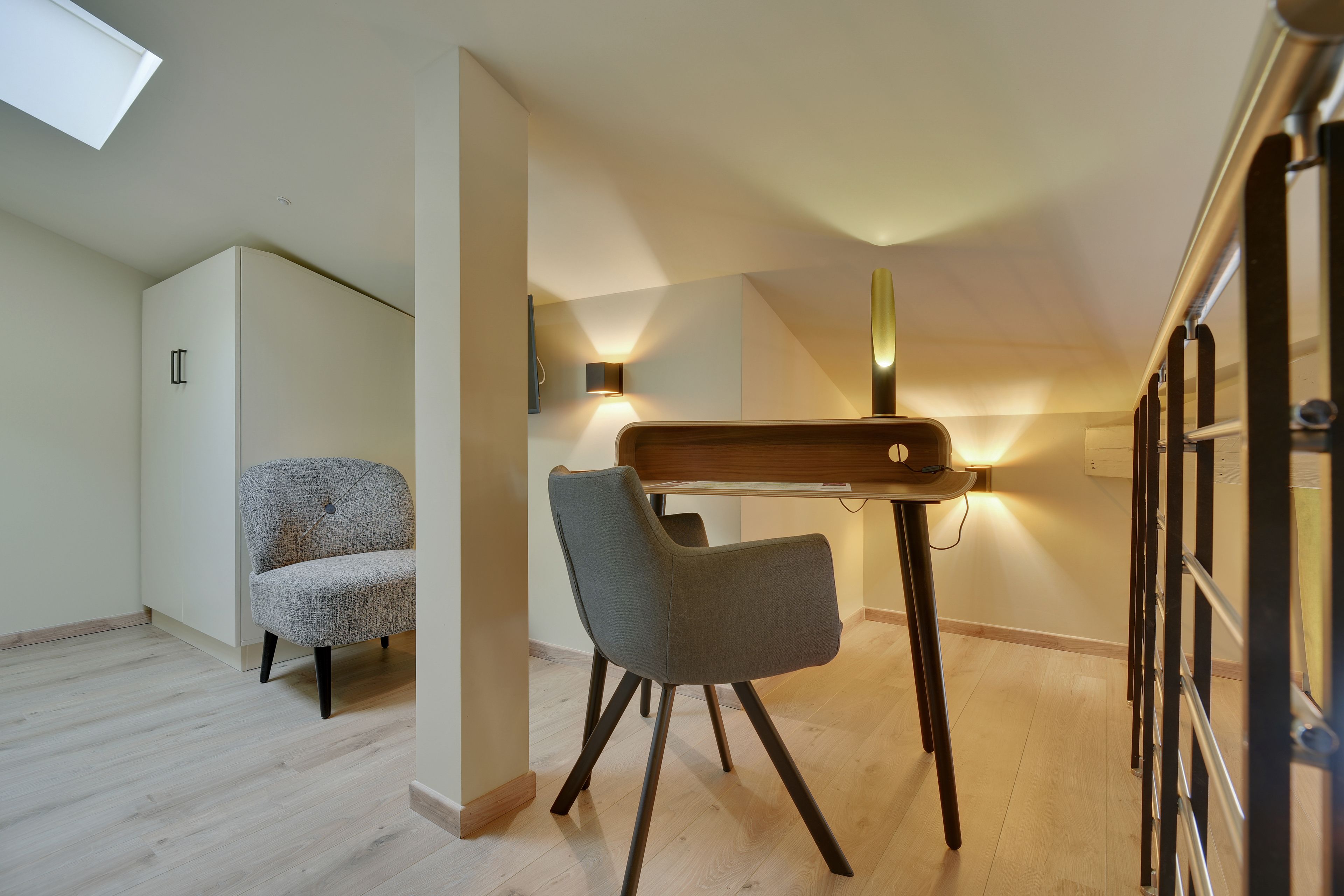 Une pièce moderne et bien éclairée, avec un bureau en bois, deux chaises et un luminaire au plafond.
