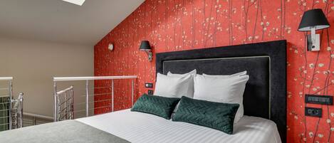 Un dormitorio con cama, mesita de noche, lámpara de pared y ventana.