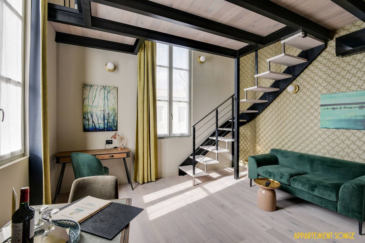 Un salon moderne avec un escalier, un bureau et un canapé vert.