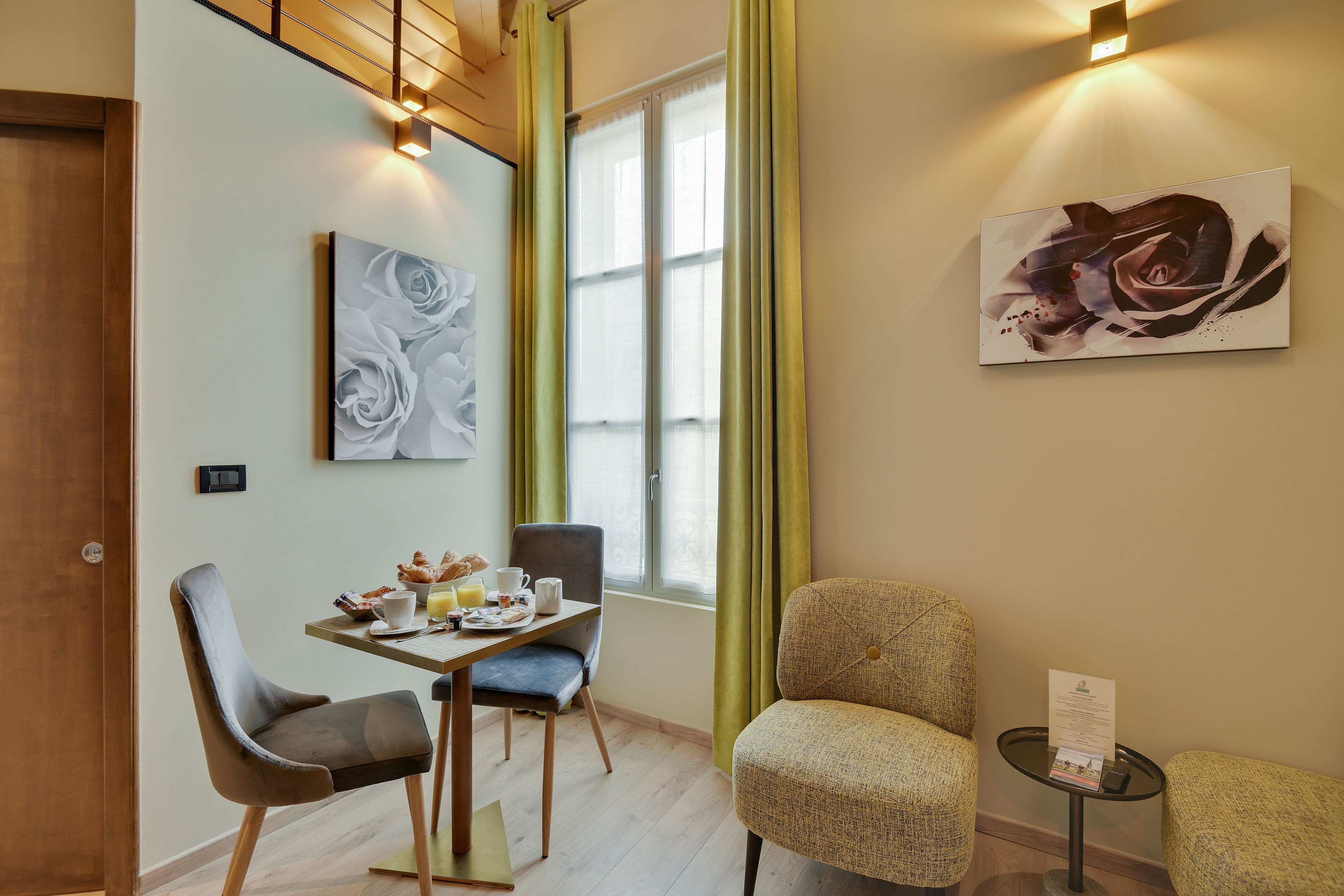 Un'area pranzo con tavolo apparecchiato per la colazione, due sedie, un tavolino con un menù e un quadro appeso alla parete.