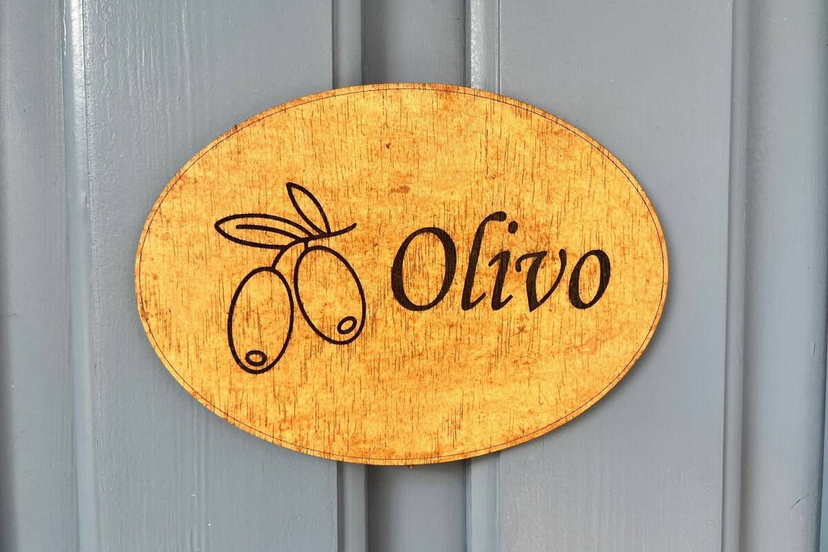 A wooden sign with the name "Olivo" and a drawing of olives.