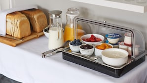 A breakfast setup with bread, milk, juice, and various fruits and yogurt on a tray. - Alton House (Sheringham)