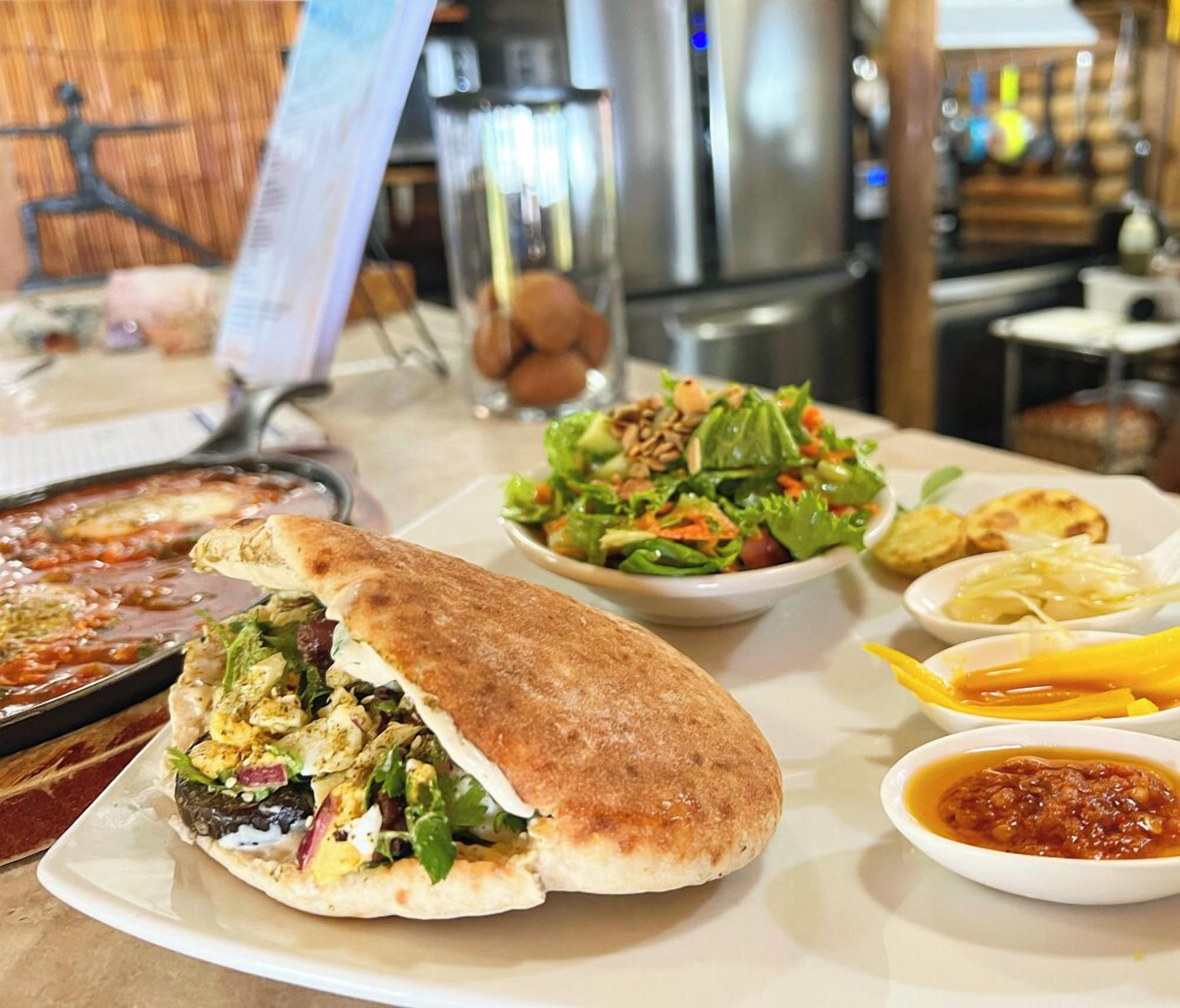A dining table with a variety of dishes including a stuffed flatbread, a salad, and a pan of food.