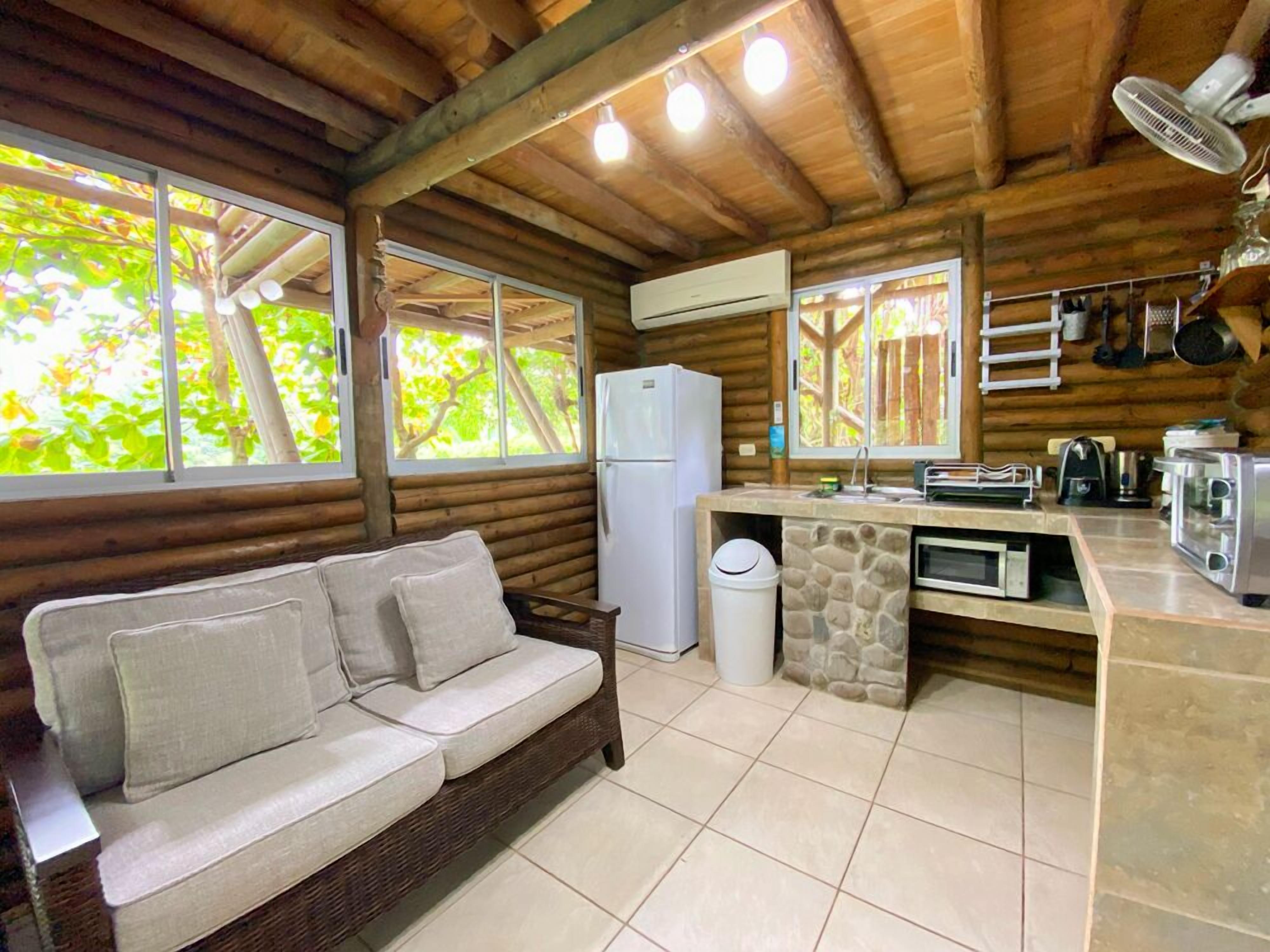 A cozy cabin-style kitchen with a stone backsplash, a built-in microwave, and a refrigerator.