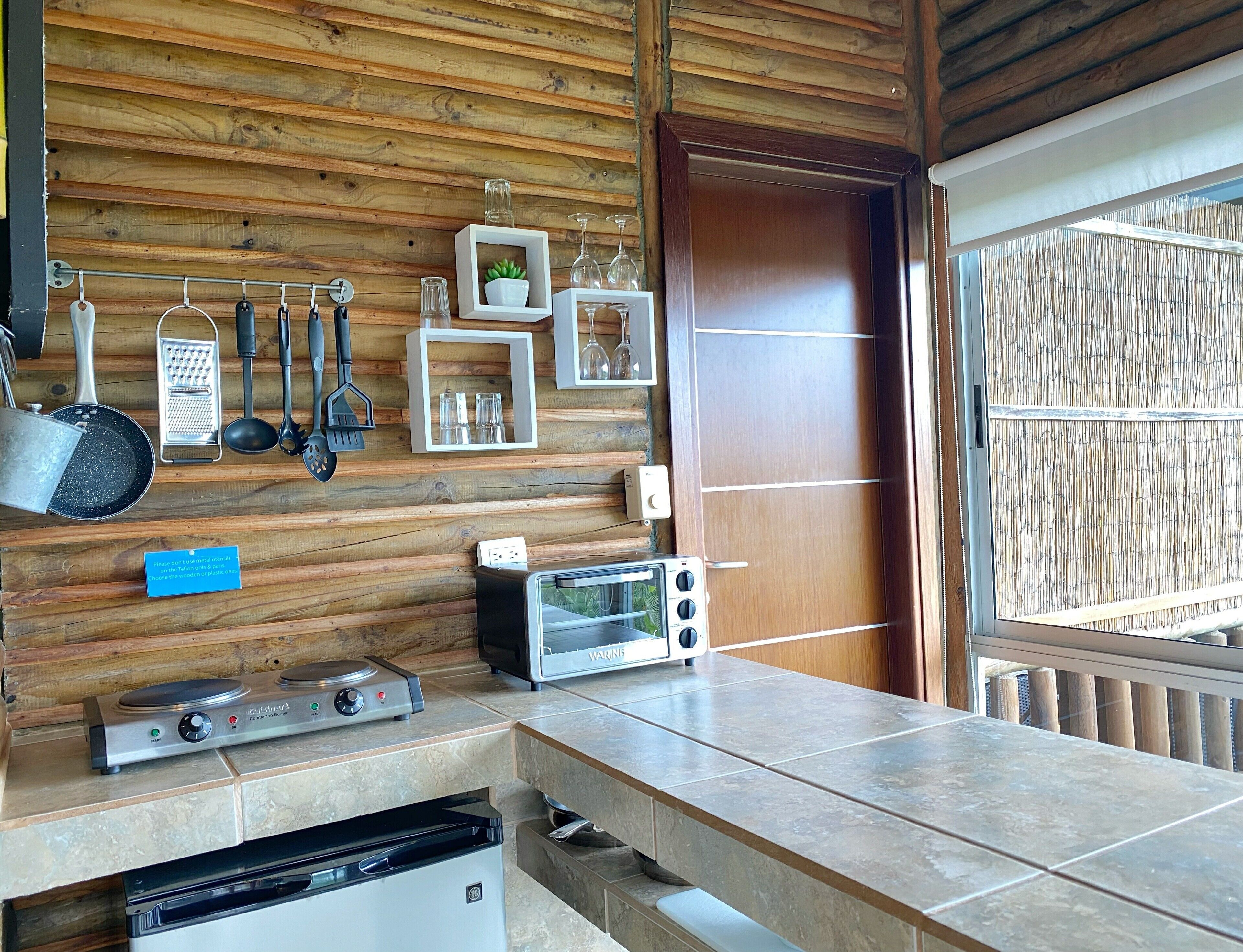 A kitchen with wooden walls, a built-in stove, a toaster, and various utensils hanging on the wall.
