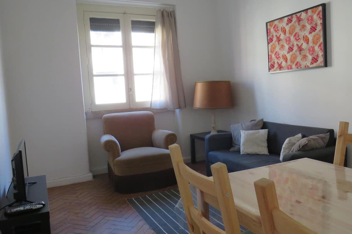 Een woonkamer met een bank, fauteuil en een tafel.