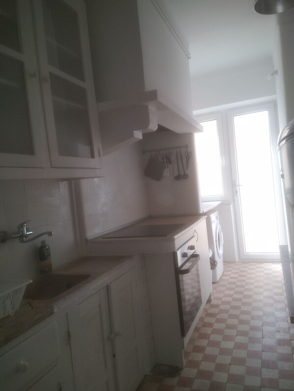 A kitchen with white cabinets, a sink, a countertop, and a washing machine.