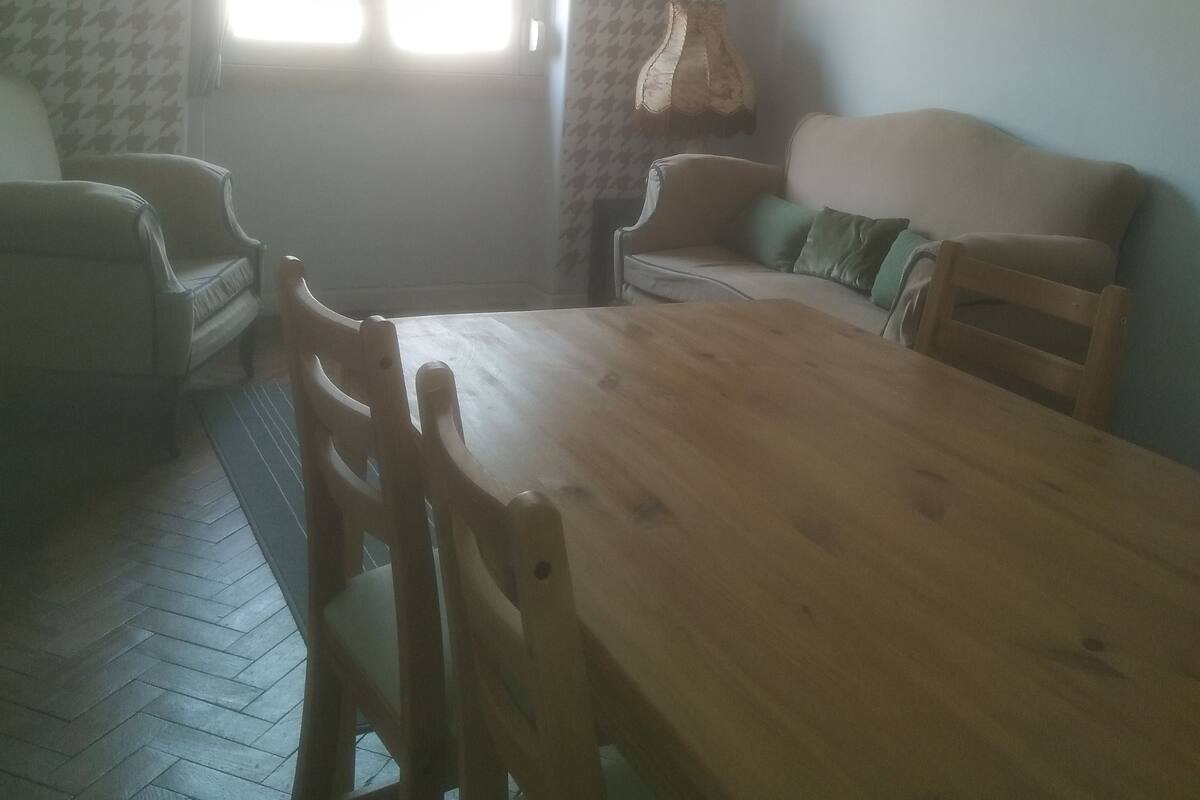 Een eethoek met een houten tafel en stoelen, een bank en behang met een patroon.