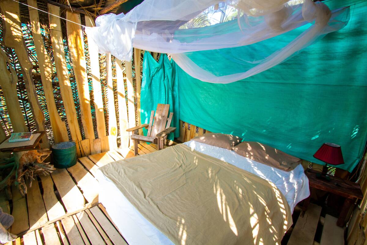 Una habitación con cama, una silla, una mesa y un mosquitero.