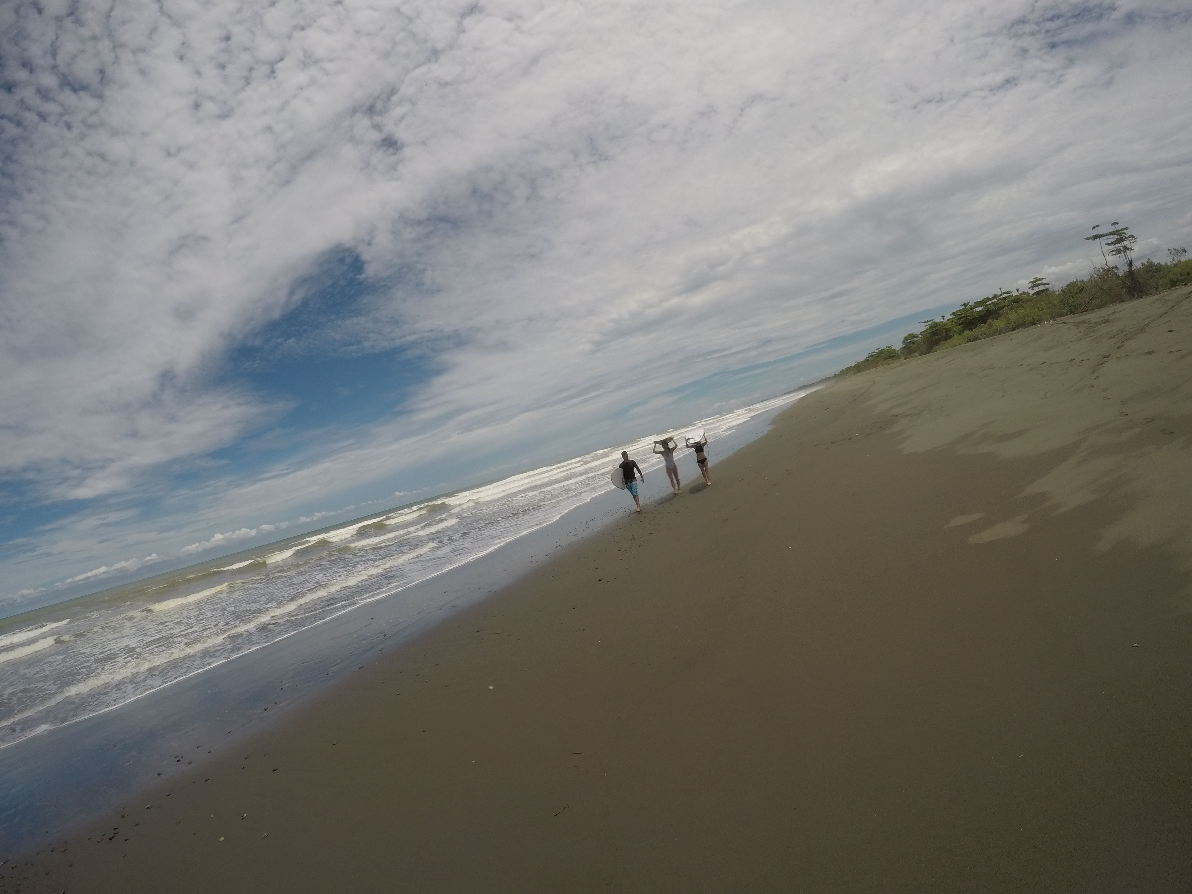 A beach with a sandy shore and a few people walking along it.