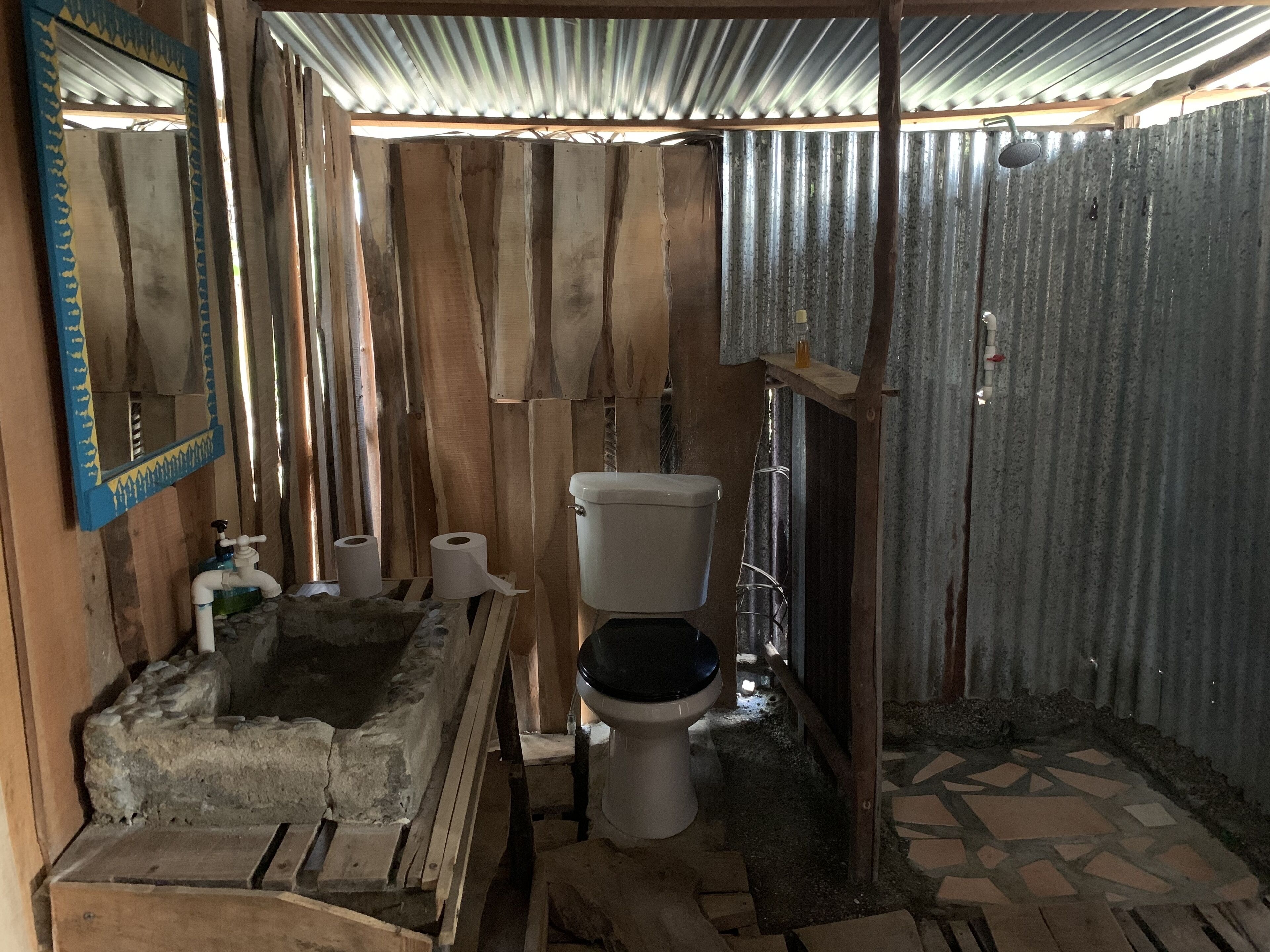 A rustic bathroom with a wooden sink, a toilet, and a mirror.
