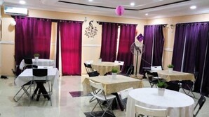 A conference room with multiple tables and chairs, purple curtains, and a ceiling fan. - DABOTOV Hotel and Suites (Ilorin)