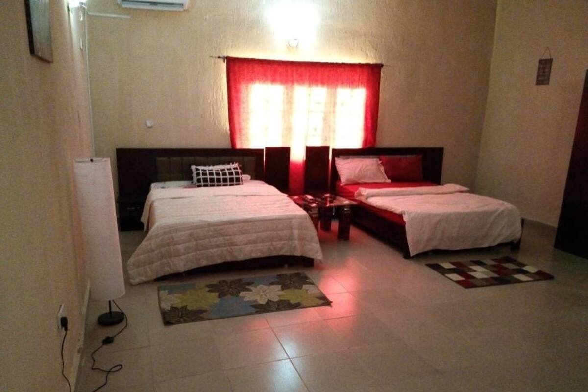 A bedroom with two beds, a red curtain, and a patterned rug.