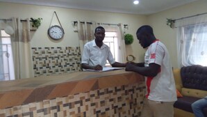 A reception area with a patterned counter, a clock, and a window with curtains. - DABOTOV Hotel and Suites (Ilorin)