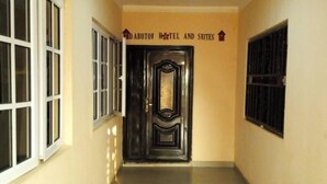 A hallway with a black door, beige walls, and a sign above the door reading "ABOTOV HOTEL AND SWITES". - DABOTOV Hotel and Suites (Ilorin)