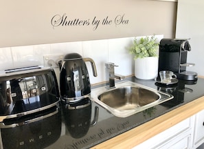 Una cocina con cafetera, hervidor y pileta.