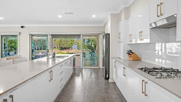 A modern kitchen with white cabinetry, a stainless steel range hood, and a large island with a sink. - CYPRESS POINT LODGE - THE VINTAGE HOLIDAY HOUSES (POKOLBIN)