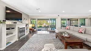 A modern living room with a fireplace, a flat-screen TV, and a sofa. - CYPRESS POINT LODGE - THE VINTAGE HOLIDAY HOUSES (POKOLBIN)
